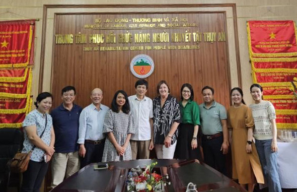 A group of people standing in front of a Vietnamese sign
